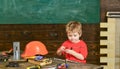 Kid playing with red screwdriver. Small boy in workshop. Tools lying on wooden table Royalty Free Stock Photo