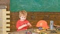 Kid playing with red screwdriver. Small boy in workshop. Tools lying on wooden table Royalty Free Stock Photo