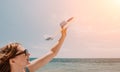 Woman hand holding toy airplane on blue sky and white clouds at sunset sea beach abstract background. Travel adventure Royalty Free Stock Photo