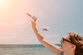 Woman hand holding toy airplane on blue sky and white clouds at sunset sea beach abstract background. Travel adventure Royalty Free Stock Photo