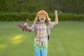 Kid playing with toy airplane and dreaming future. Happy boy pilot play with airplane outdoors.