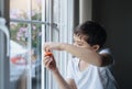 Kid playing with toy and looking at the midge climbing up outside of double glazed window. Boy sitting next to window looking out Royalty Free Stock Photo