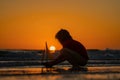 Kid playing with toy sailboat on sea beach at the summer sunset time. Sunset silhouette of child boy dreaming on cruise Royalty Free Stock Photo