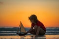 Kid playing with toy sailing boat, toy ship. Travel and adventure concept. Child feeling adventurous while cruising. Kid Royalty Free Stock Photo