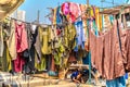 Kid playing under vibrant hanging clothes outdoors on a sunny day in Mumbai, India