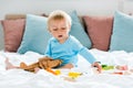 Kid playing with wooden biplane near colorful toy blocks on bed Royalty Free Stock Photo