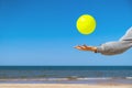 Kid playing with yellow beach ball on the sand by the sea water on a sunny day. Copy space for text. Vacation background Royalty Free Stock Photo