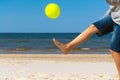 Kid playing with yellow beach ball on the sand by the sea water on a sunny day. Copy space for text. Vacation background Royalty Free Stock Photo