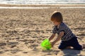 The kid plays with a bucket and a shovel in the sand. Little boy on the beach. Royalty Free Stock Photo