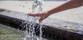 Kid plays in city fountain. Stream, splash of clean water on hand.  Refreshing water in summer heat sunny day in city park Royalty Free Stock Photo