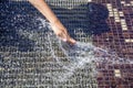 Kid plays in city fountain. Stream, splash of clean water on hand.  Refreshing water in summer heat sunny day in city park Royalty Free Stock Photo