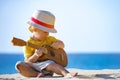 Kid plays on ukulele or small guitar at sea beach Royalty Free Stock Photo