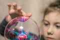 Kid plays witchcraft and magic. finger touch the plasma ball, selective focus