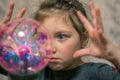 Kid plays witchcraft and magic. Portrait of a little girl playing with a plasma ball
