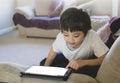 Kid pointing finger on Mock up tablet screen,Child boy lying on sofa relaxing at home watching cartoons or playing games on Royalty Free Stock Photo