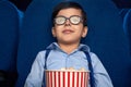 Kid with popcorn bucket watching cartoon in cinema.