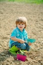Kid portrait on farmland. Cute little boy watering flowers in the spring garden. Child care plants. Happy little farmer