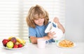 Kid pouring whole cows milk. Kid preteen boy 7, 8, 9 years old eating healthy food vegetables. Breakfast with milk Royalty Free Stock Photo