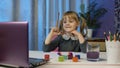 Kid pupil girl artist sitting and painting on paper, drawing coloring picture rainbow with paints Royalty Free Stock Photo