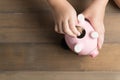 Kid put coin to piggy bank on the vintage wood background Royalty Free Stock Photo