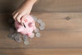 Kid put coin to piggy bank on the vintage wood Royalty Free Stock Photo