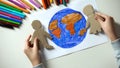 Kid putting paper family on Earth painting, environmental saving concept