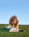 Kid read book in park on green grass lawn. Royalty Free Stock Photo
