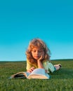 Kid read book in park on green grass lawn. Royalty Free Stock Photo