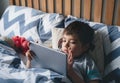 Kid reading bed time stories on tablet before sleep, Happy boy sitting in bed playing games on digital pad, Child relaxing at home Royalty Free Stock Photo