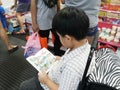 a kid reading a cartoon book at the book fair in Bangkok Royalty Free Stock Photo