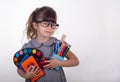 Kid ready for school. Cute clever child in eyeglasses holding school supplies: pens, notebooks, scissors and apple.