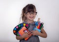 Kid ready for school. Cute clever child in eyeglasses holding school supplies: pens, notebooks, scissors and apple.