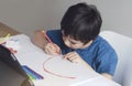 Kid red pen colouring rainbow on paper,Child using digital tablet for homework online lesson,Boy enjoy art activity at home, self- Royalty Free Stock Photo