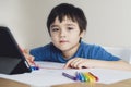 Kid red pen colouring rainbow on paper,Child using digital tablet for homework online lesson,Boy enjoy art activity at home, self-