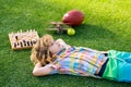Kid relax in park, laying on grass, daydreaming. Board game in backyard, laying on grass.