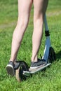Kid rides push-bicycle on green grass, close-up rear view at legs wearing shoes Royalty Free Stock Photo