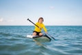 Kid riding on a paddle board. Summer holidays. Kid paddle surf surfer little blonde boy in summer beach. Happy Child Royalty Free Stock Photo