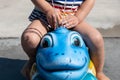 Kid riding on swinging fun animal head with splash water, closeup shot Royalty Free Stock Photo