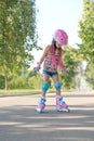 Kid on roller skates in full sports gear is standing on sidewalk trying to make first move. Royalty Free Stock Photo