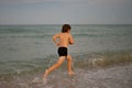 Kid running and splashing in the sea. Summer vacation. Child Running Along the beach. Active little kid running along Royalty Free Stock Photo