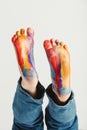 Kid`s feet painted in rainbow colors.