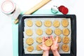 Kid`s hands hold unbaked cookies over pan with cookies. Close-up of child`s hands. Step by step instructions