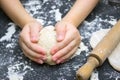 Kid`s hands, some flour, wheat dough and rolling pin on the black table. Children hands making the rye dough for backing bread. S Royalty Free Stock Photo