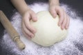 Kid`s hands, some flour, wheat dough and rolling pin on the black table. Children hands making the rye dough for backing bread. Royalty Free Stock Photo