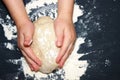 A kid`s hands, some flour, wheat dough and rolling pin on the black table with a place for text. Children hands making the rye do Royalty Free Stock Photo