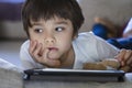 Kid sad face looking deep in thought, Bored Child boy lying on sofa playing game on tablet ,Home schooling,Social Distance,E- Royalty Free Stock Photo