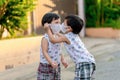 Kid in safety wearing mask in town. Twin Children wearing medical face mask outdoor. Twin Child helps to put a mask on his face t