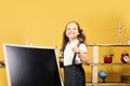 Kid and school supplies, yellow background. Schoolgirl with cheerful face Royalty Free Stock Photo