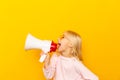 Kid shouting through megaphone. Communication concept. yellow background as copy space for your text Royalty Free Stock Photo