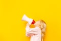 Kid shouting through megaphone. Communication concept. yellow background as copy space for your text. Royalty Free Stock Photo